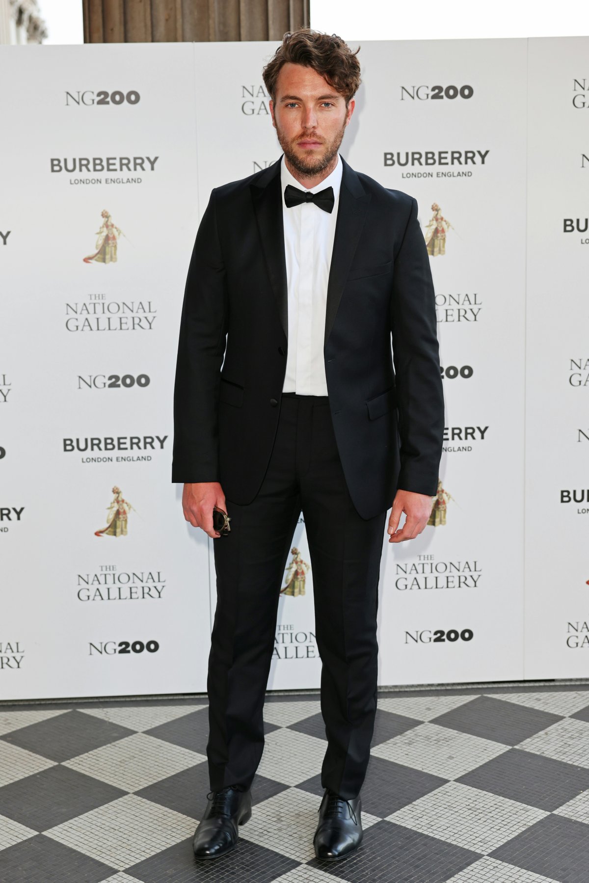 Tom Hughes in a black suit on a white background.