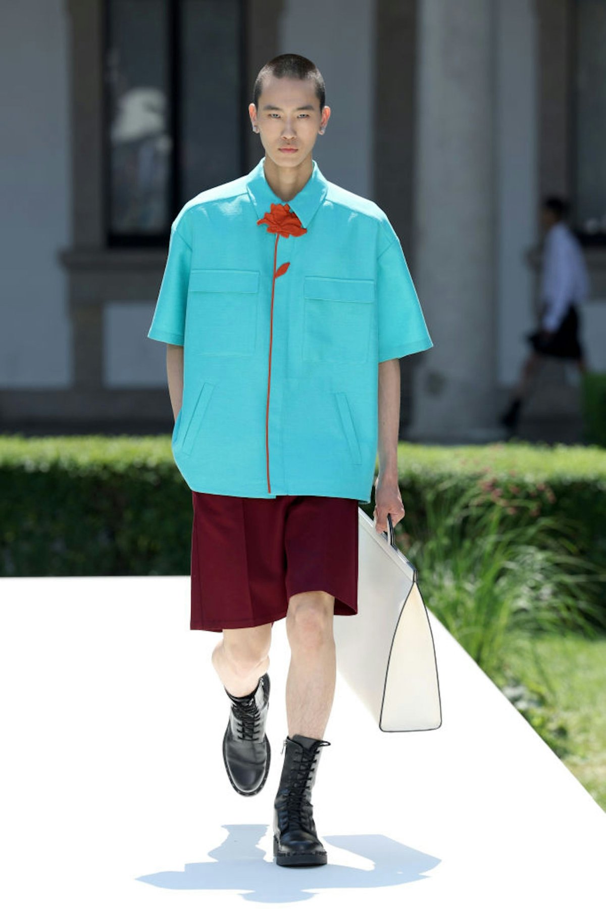 A model in a blue button down and brown shorts.