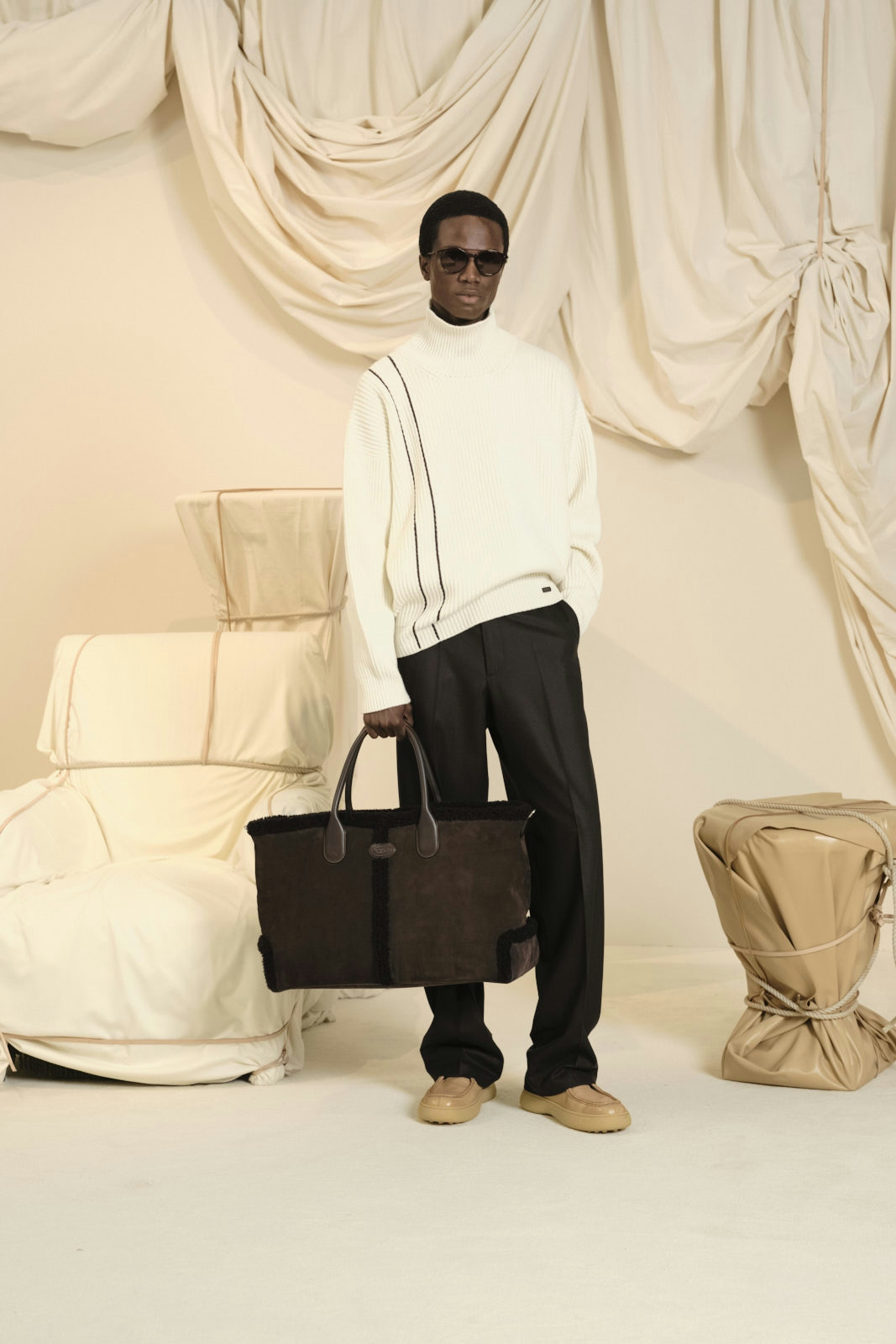 person standing clothing knitwear sweater accessories bag handbag sitting