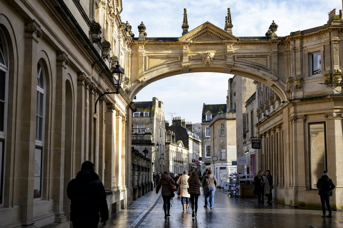 photo of roman bath archway with pedestrians walking on the street
