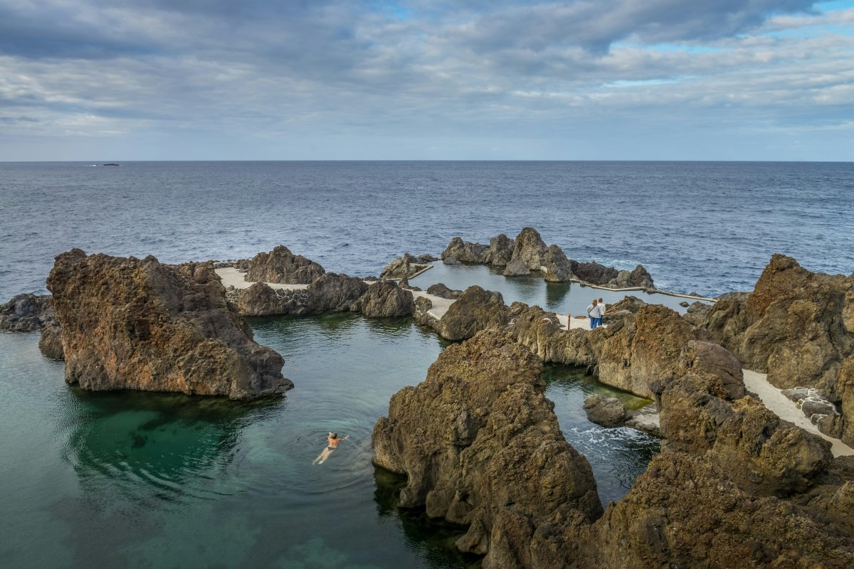 person swimming in natural tide pool near ocean