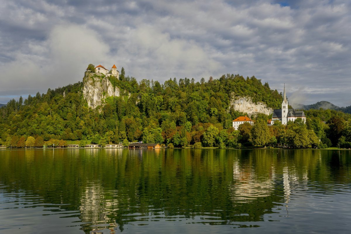 church on cliffside with forest on shore of lake